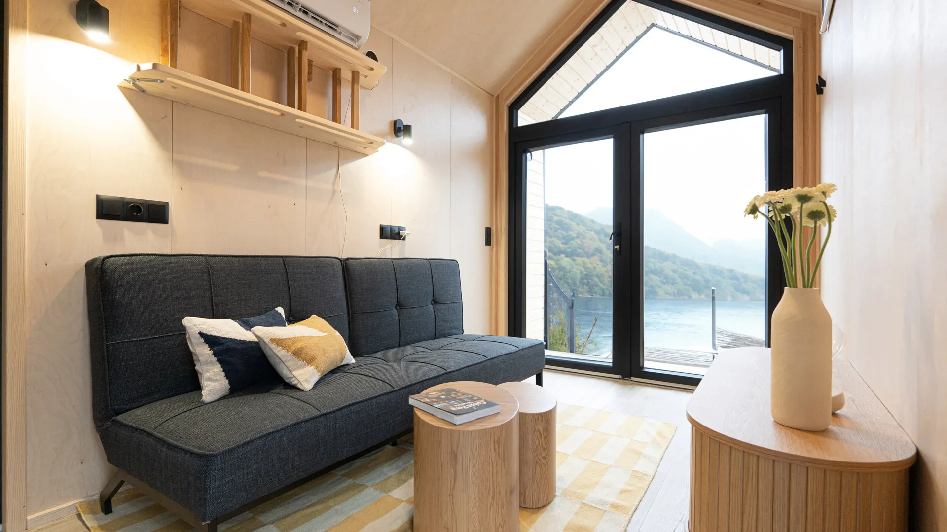 Sofa vor bodentiefem Giebelfenster mit Seeblick